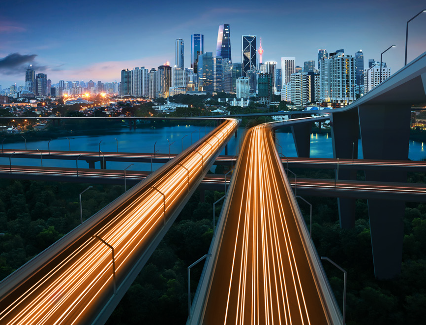 Light streaks from cars in a slow shutter-speed photograph on a highway overlooking a city